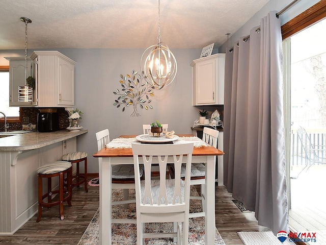 dining area featuring a chandelier, a textured ceiling, and dark hardwood / wood-style flooring