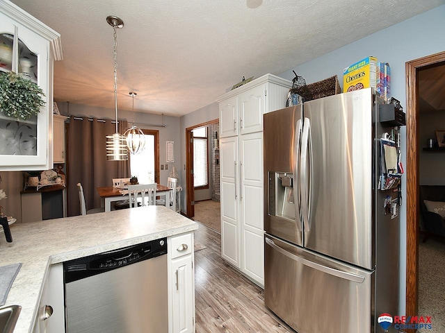 kitchen with hanging light fixtures, a textured ceiling, appliances with stainless steel finishes, white cabinetry, and a chandelier