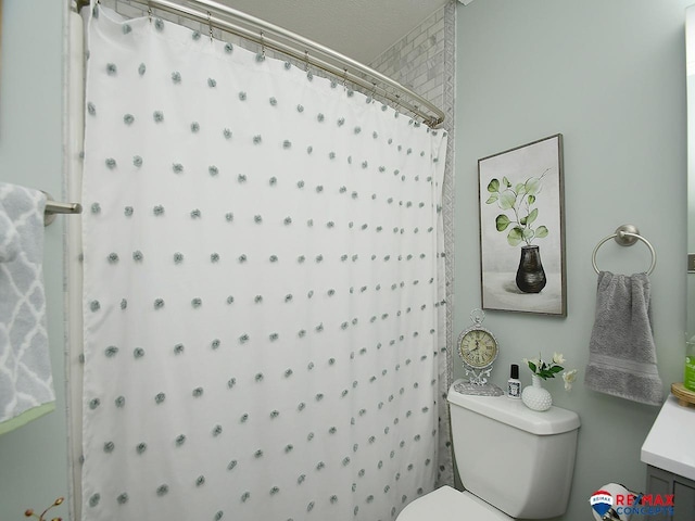 bathroom with curtained shower, vanity, and toilet