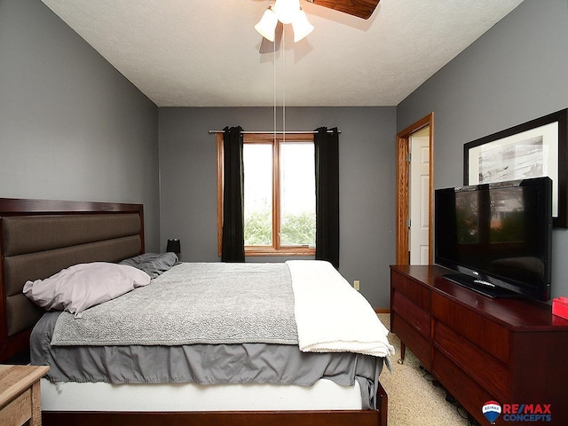 bedroom featuring ceiling fan, light colored carpet, and a textured ceiling