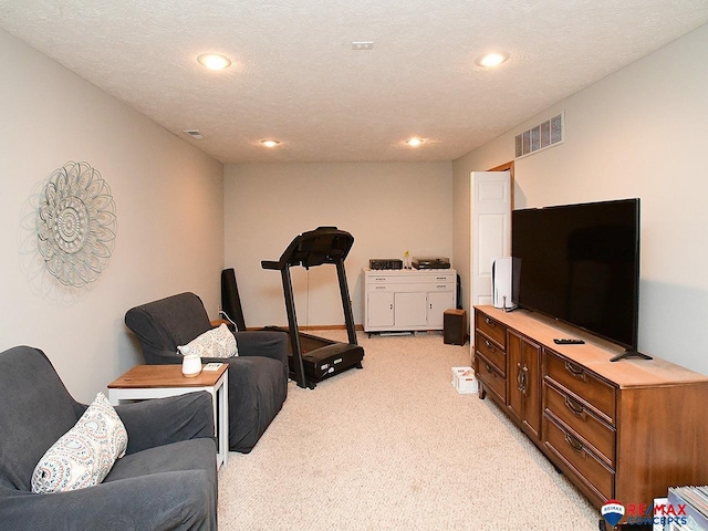 workout room with light colored carpet and a textured ceiling