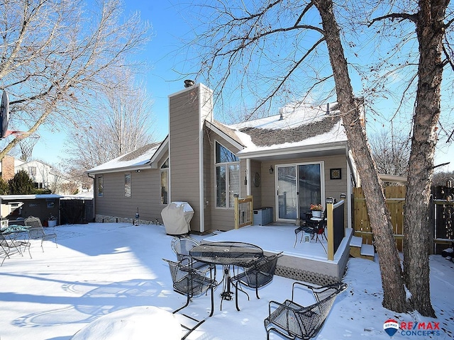 snow covered back of property with a wooden deck