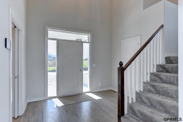 foyer featuring wood-type flooring and a towering ceiling