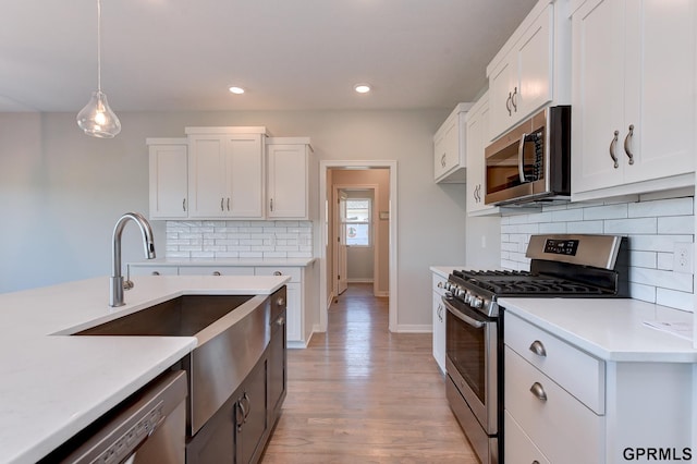 kitchen with white cabinets, pendant lighting, stainless steel appliances, and tasteful backsplash