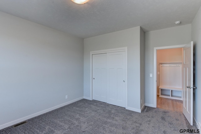 unfurnished bedroom featuring carpet flooring, a textured ceiling, and a closet