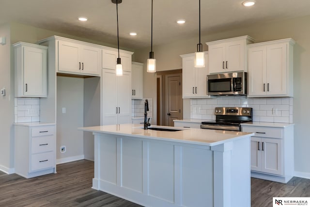 kitchen with white cabinets, a kitchen island with sink, hanging light fixtures, and appliances with stainless steel finishes