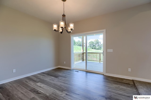 empty room featuring dark wood-type flooring and an inviting chandelier