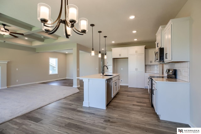 kitchen featuring beam ceiling, white cabinetry, a kitchen island with sink, and appliances with stainless steel finishes