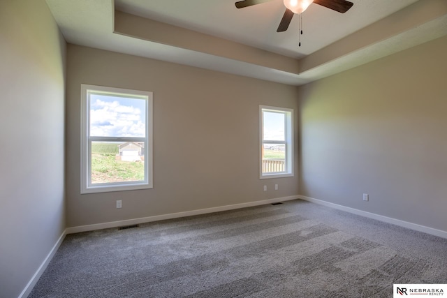 unfurnished room with carpet flooring, a tray ceiling, and ceiling fan