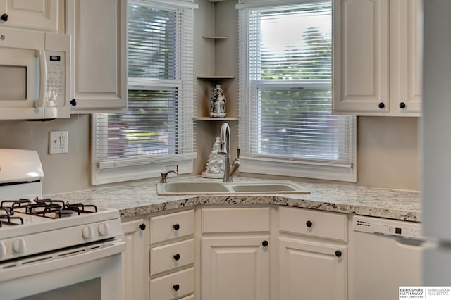 kitchen featuring white cabinets, light stone counters, white appliances, and sink