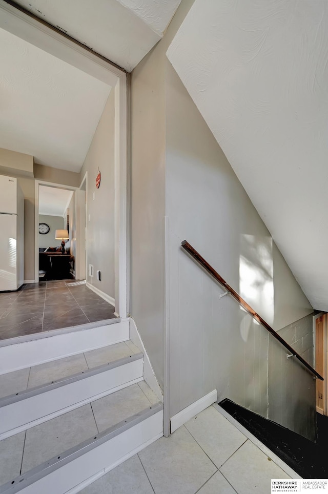 staircase with tile patterned floors and vaulted ceiling