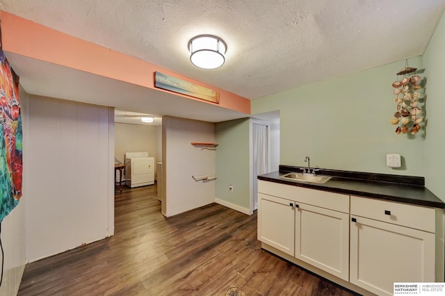 kitchen featuring dark hardwood / wood-style flooring, sink, a textured ceiling, and washer / dryer