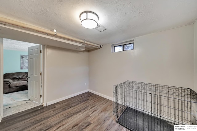 basement with wood-type flooring and a textured ceiling