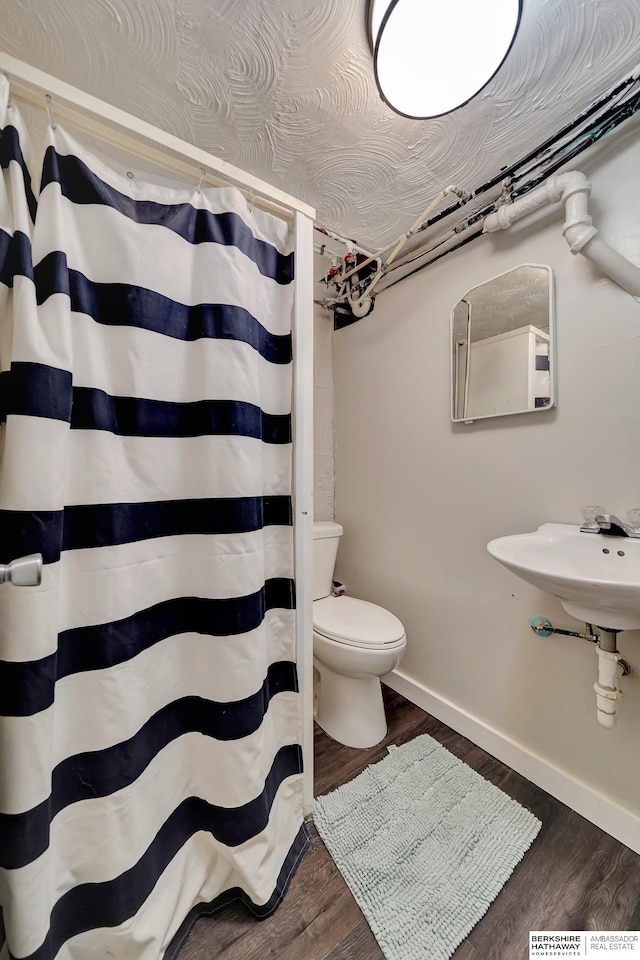 bathroom with hardwood / wood-style flooring, sink, a textured ceiling, and toilet