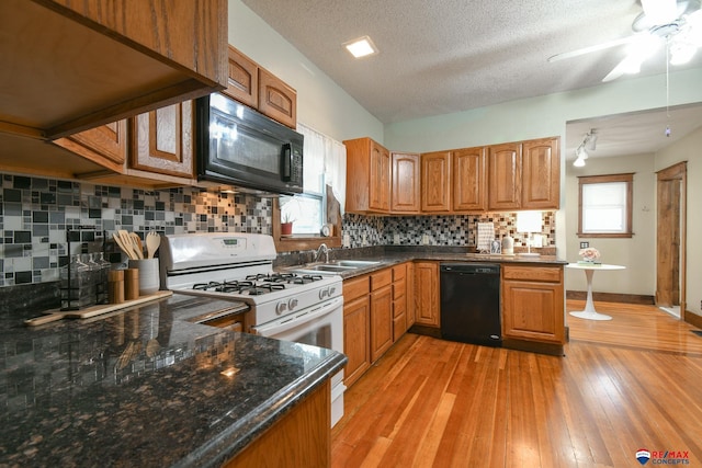 kitchen with sink, tasteful backsplash, kitchen peninsula, a textured ceiling, and black appliances