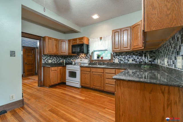 kitchen featuring tasteful backsplash, light hardwood / wood-style flooring, white range, dark stone counters, and a textured ceiling