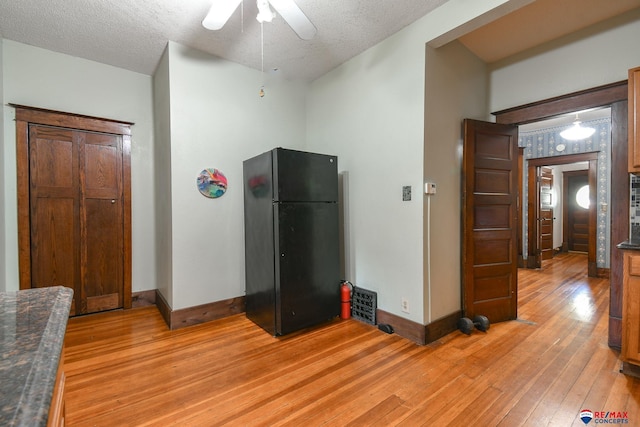 kitchen with ceiling fan, black refrigerator, a textured ceiling, and light hardwood / wood-style flooring