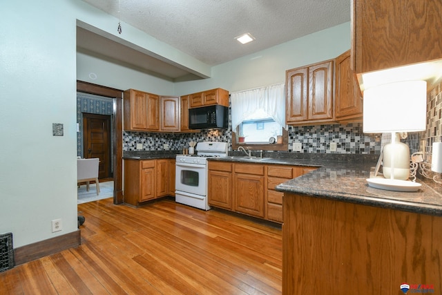 kitchen featuring light wood-type flooring, a textured ceiling, backsplash, and white gas stove