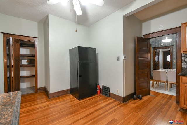 kitchen featuring ceiling fan, black refrigerator, light wood-type flooring, and a textured ceiling