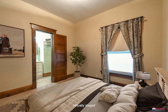 bedroom featuring connected bathroom, light carpet, and a textured ceiling