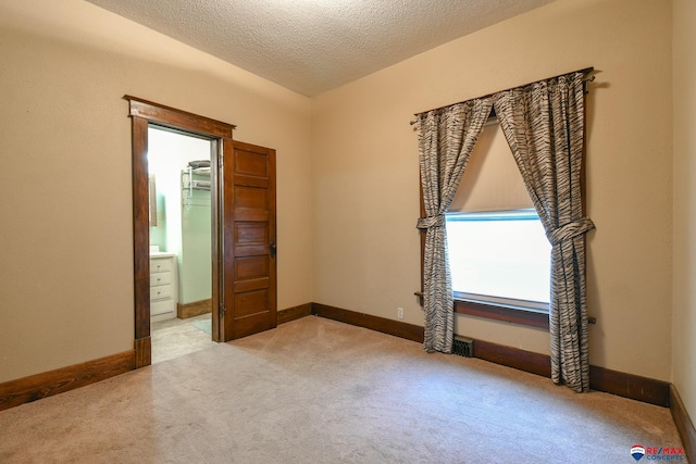 empty room with light carpet and a textured ceiling