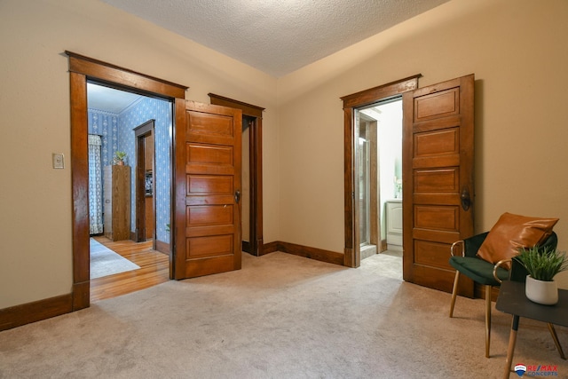 interior space featuring a textured ceiling, light colored carpet, and lofted ceiling