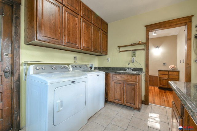 laundry room with cabinets, light tile patterned floors, separate washer and dryer, and sink