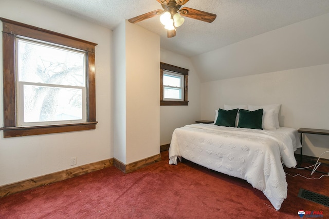 carpeted bedroom with a textured ceiling, vaulted ceiling, and ceiling fan