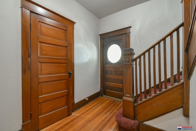 foyer entrance with light wood-type flooring and a textured ceiling