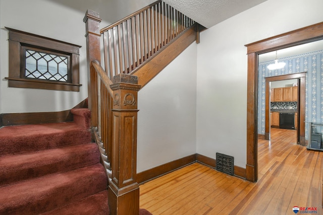 stairway with a chandelier and hardwood / wood-style flooring