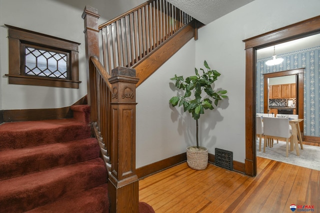 staircase featuring hardwood / wood-style floors and a notable chandelier