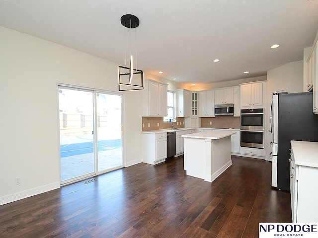 kitchen with stainless steel appliances, sink, a center island, white cabinetry, and hanging light fixtures