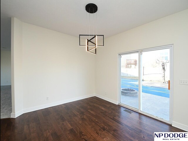 unfurnished dining area with dark wood-type flooring and a notable chandelier