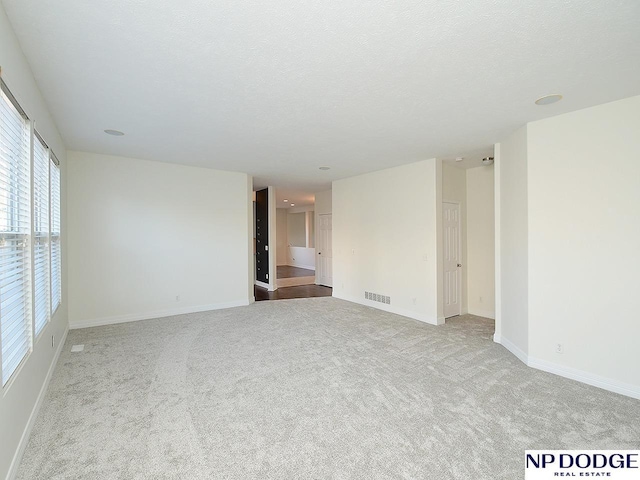 empty room with a textured ceiling and light carpet