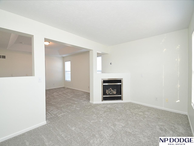 unfurnished living room with light carpet and a textured ceiling