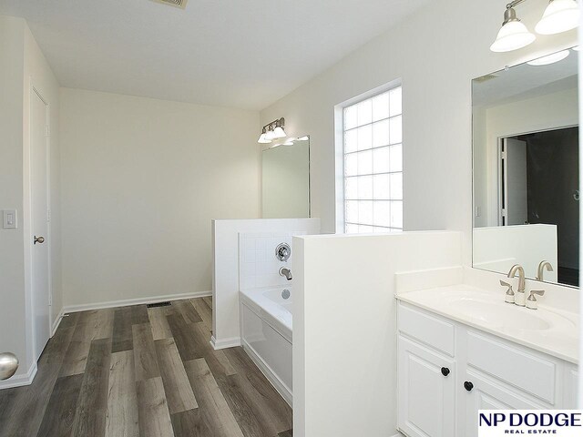 bathroom with hardwood / wood-style floors, vanity, and a tub to relax in