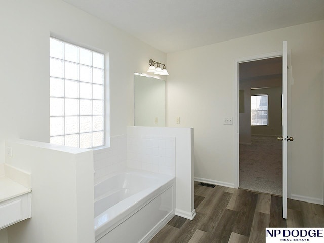 bathroom featuring wood-type flooring, vanity, and a tub