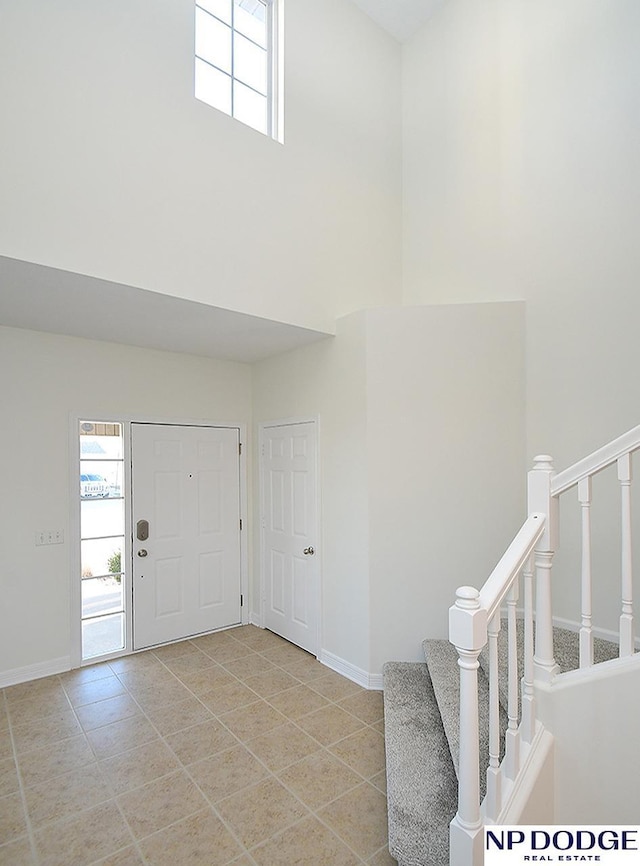 foyer entrance featuring light tile patterned floors and a towering ceiling