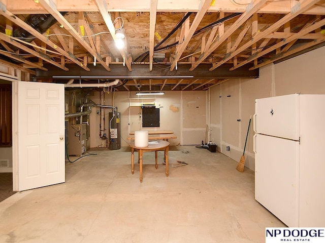 basement with heating unit, white fridge, and water heater