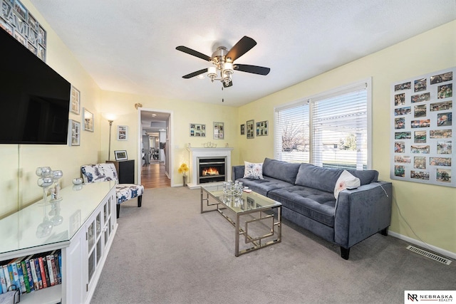 living room with light carpet, a textured ceiling, and ceiling fan