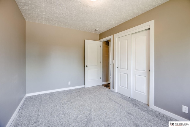 unfurnished bedroom featuring carpet, a textured ceiling, and a closet