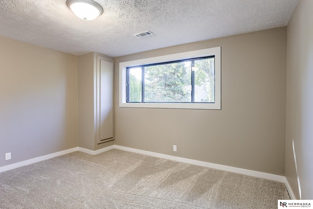 carpeted empty room with a textured ceiling