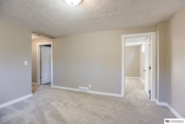 empty room featuring light colored carpet and a textured ceiling