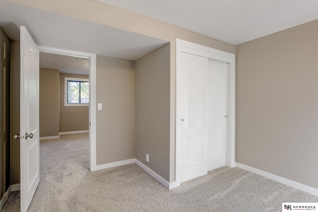 unfurnished bedroom with light carpet and a closet