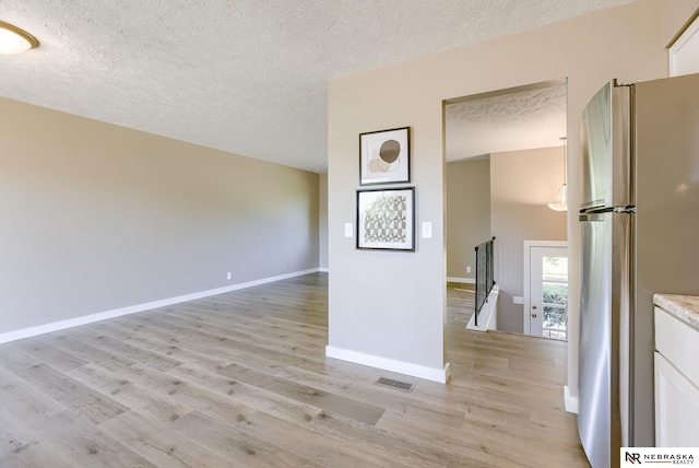 interior space with a textured ceiling and light hardwood / wood-style floors