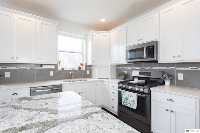 kitchen with white cabinets, backsplash, stainless steel appliances, and sink