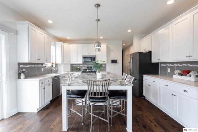 kitchen featuring appliances with stainless steel finishes, white cabinetry, and hanging light fixtures