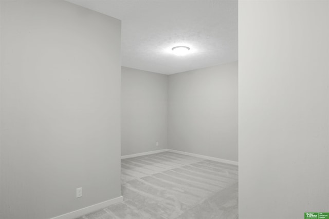 empty room featuring a textured ceiling and light carpet