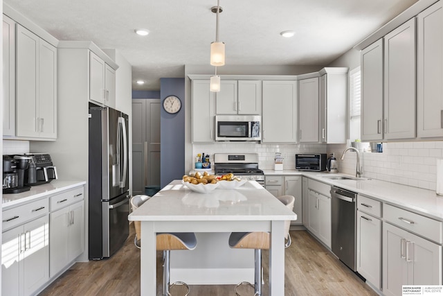 kitchen featuring sink, hanging light fixtures, a breakfast bar area, light wood-type flooring, and stainless steel appliances