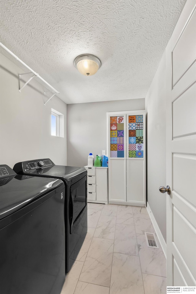 laundry room with a textured ceiling and washing machine and clothes dryer